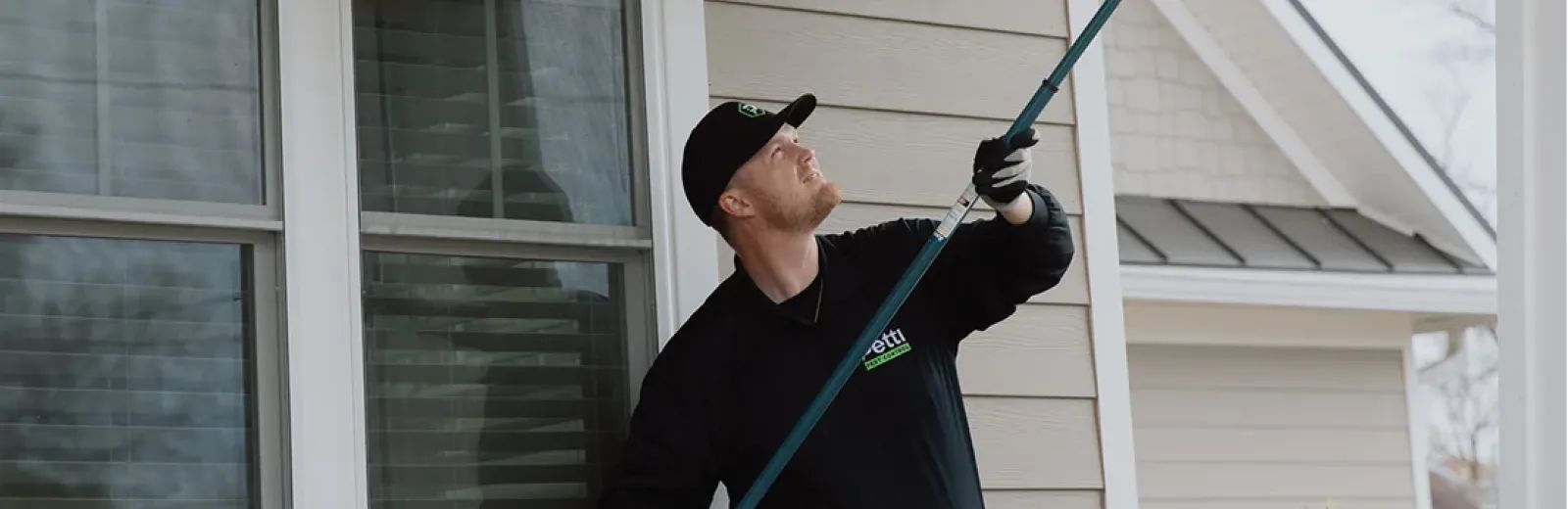 technician sweeping exterior of house