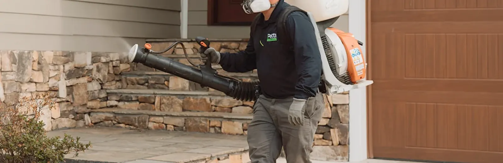 technician spraying shrubs around house mosquito prevention